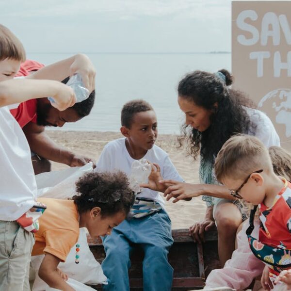 A group of children volunteering to clean a beach with a Save the Earth sign