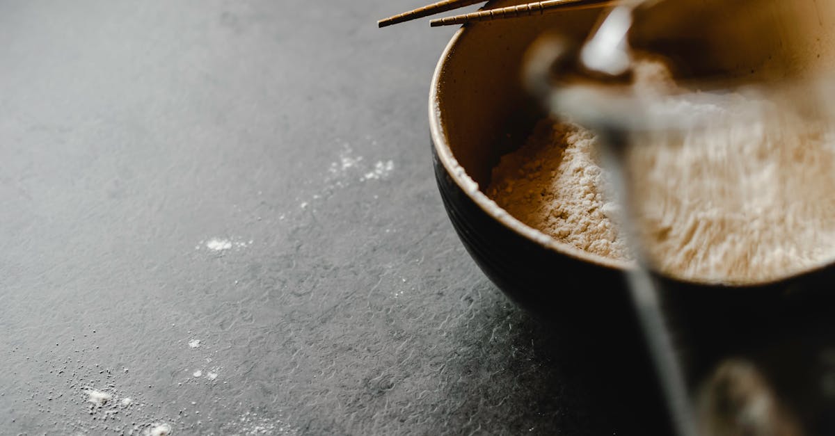 Close-up of a bowl filled with flour and chopsticks on a textured gray surface