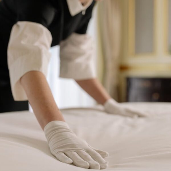 A housekeeper straightening the bed linens in a well-appointed hotel room