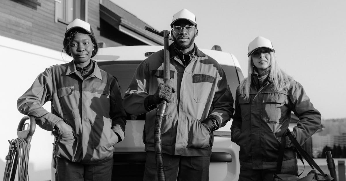 Three professional cleaners in uniform pose with equipment in front of a building