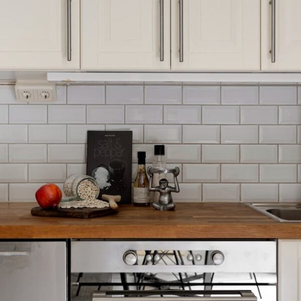 Stylish modern kitchen interior with white cabinets and wooden countertop, featuring kitchen essentials