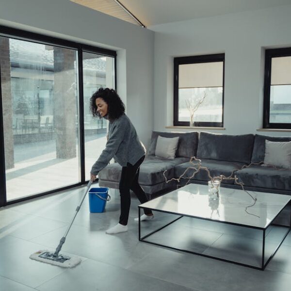 A woman mopping the floor in a bright, modern living room