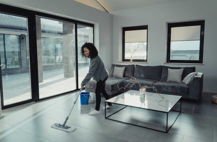 A woman mopping the floor in a bright, modern living room