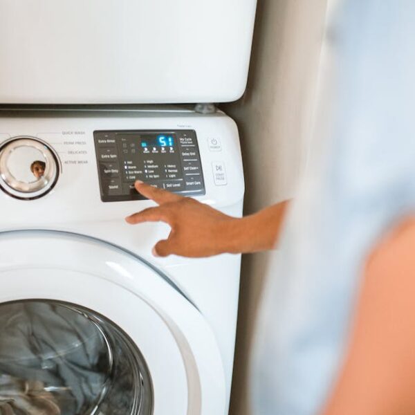 Hand selecting laundry options on a digital washing machine control panel indoors