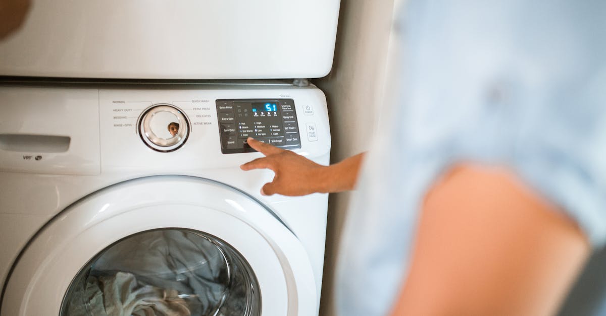 Hand selecting laundry options on a digital washing machine control panel indoors