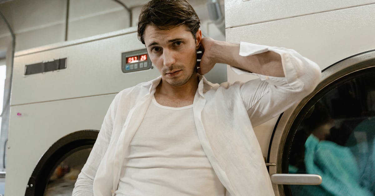 Young man in a white shirt leaning on a washing machine in a laundry facility