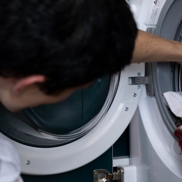 Close-up of a man placing clothes into a washing machine during household chores