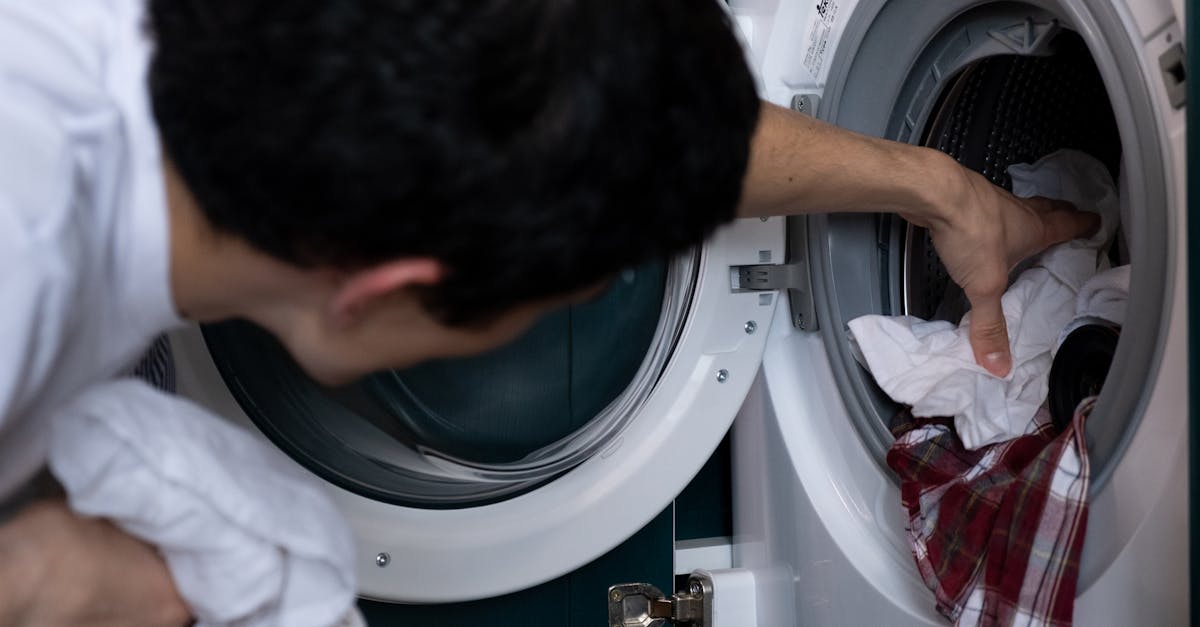 Close-up of a man placing clothes into a washing machine during household chores